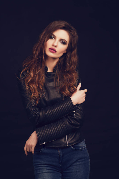 Portrait de la belle jeune femme aux cheveux bruns ondulés posant en studio sur fond noir. tonique
. - Photo, image