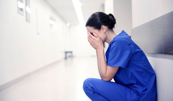 sad or crying female nurse at hospital corridor - Zdjęcie, obraz