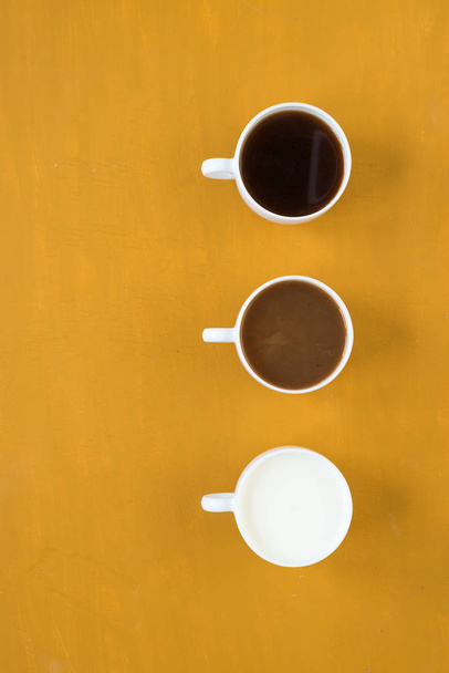 黄色の背景にミルクとコーヒー 3 杯 - 写真・画像