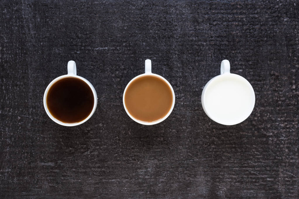 Three cups with coffee and milk on black background - Фото, изображение