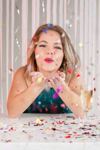 Happy girl blowing colourful glitter at a party - 写真・画像