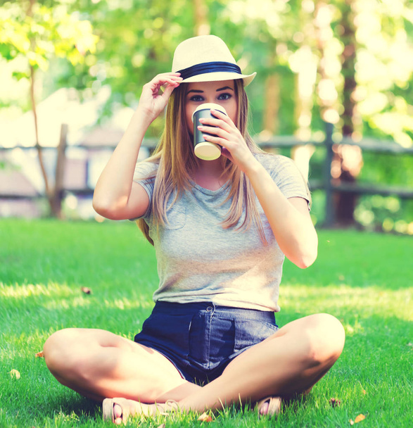 Young woman drinking coffee outside - Fotoğraf, Görsel