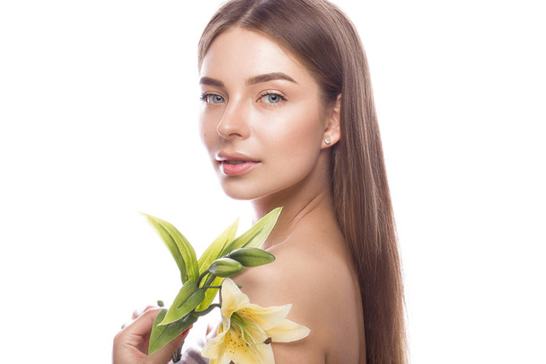 Beautiful young girl with a light natural make-up and perfect skin with flowers in her hand . Beauty face. - Valokuva, kuva