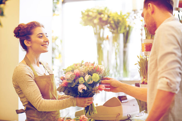 smiling florist woman and man at flower shop - Foto, Bild
