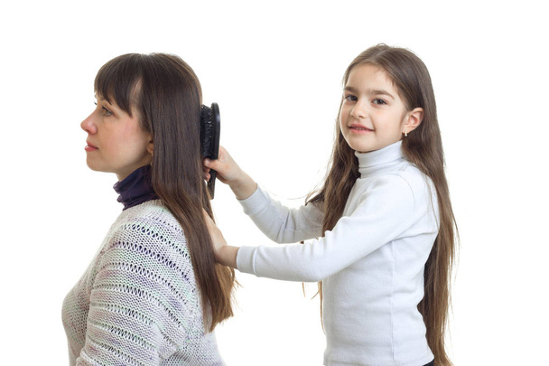 cute girl combing her hair and her mother smiling - Fotografie, Obrázek