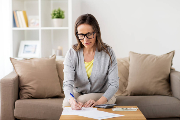 woman with money, papers and calculator at home - Foto, Imagen