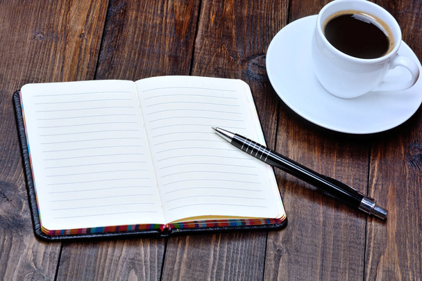 Notebook with pen and coffee cup on desk - Photo, Image