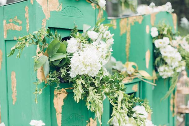 Beautifully decorated photo zona for wedding. Green chest of drawers decorated with white flowers - Photo, Image