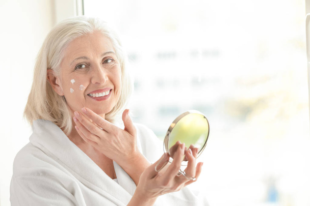 elderly woman  applying face cream  - Fotó, kép