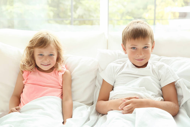 Portrait of little boy and girl in bed - 写真・画像
