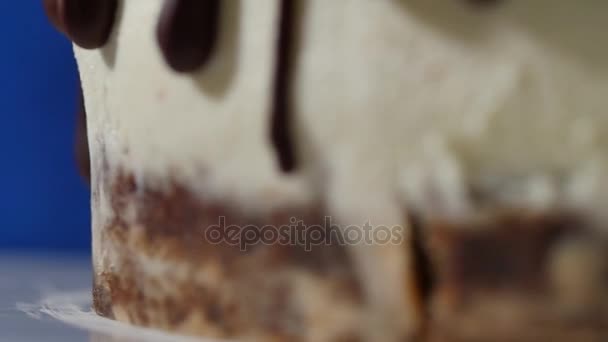 Крупним планом частина шоколадного торта з білими лініями і замороженими краплями - харчовий фон. Шоколадні потоки ізольовані на білому. крупним планом шоколадний сироп на торті на темно-синьому фоні
. - Кадри, відео