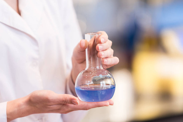 vaso de precipitados con líquido en manos de mujeres científicas
 - Foto, Imagen