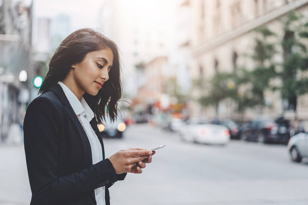 Piękna kobieta, odpowiadając na wiadomości za pośrednictwem telefonu komórkowego podczas spaceru w centrum miasta - Zdjęcie, obraz