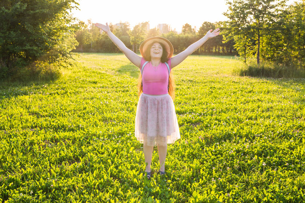 freie, glückliche junge Frau, die die Arme hebt und die Sonne im Hintergrund bei Sonnenaufgang beobachtet - Foto, Bild