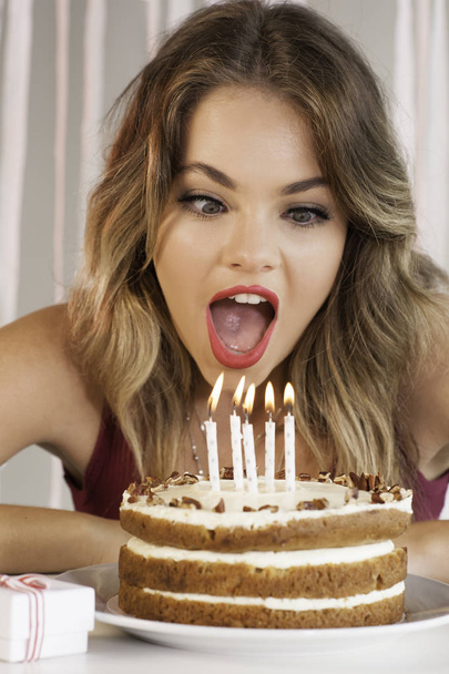young attractive birthday girl blowing out candles on a cak - Фото, зображення