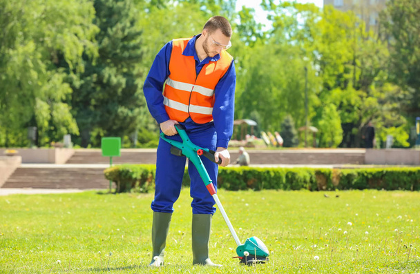 worker mowing lawn with grass trimmer  - Foto, Bild