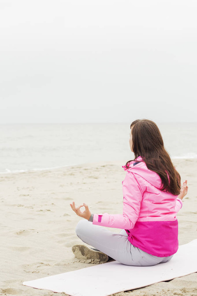 mujer practica yoga y medita en la posición de loto en la playa
 - Foto, Imagen