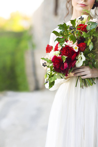 Nevěsta v bílých svatebních šatech drží krásnou kytici nad rozostření - Fotografie, Obrázek