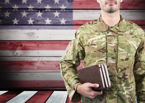 Soldier holding books in front of the american flag - Valokuva, kuva