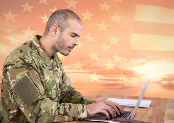 Soldier using a laptop in front of american flag - Φωτογραφία, εικόνα