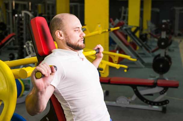 Hombre atlético haciendo entrenamientos con máquina de ejercicio de energía en un club de gimnasio
. - Foto, imagen