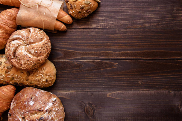 Fresh bread on the dark wooden background top view - Foto, imagen