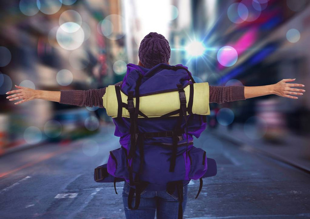 Back of millennial backpacker arms outstretched against blurry street - Photo, Image