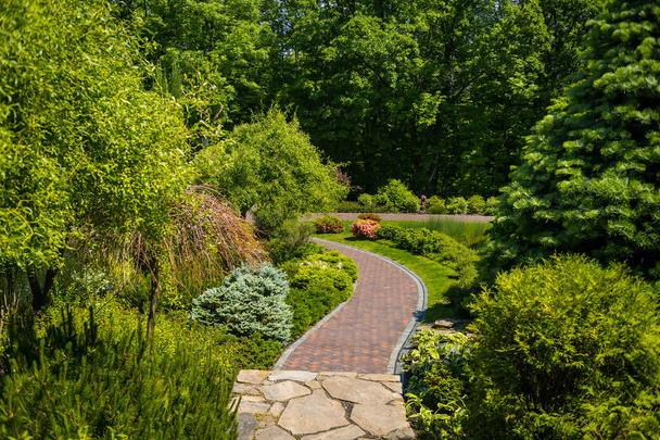 Landscaping in the garden. The path in the garden.Beautiful backyard landscape design,Some flowers and nicely trimmed bushes on the leveled front yard,Landscape formal - Photo, Image