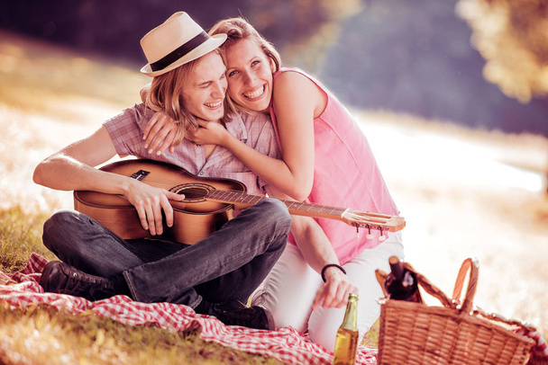 Чоловік грає на гітарі з дівчиною на пікніку
 - Фото, зображення