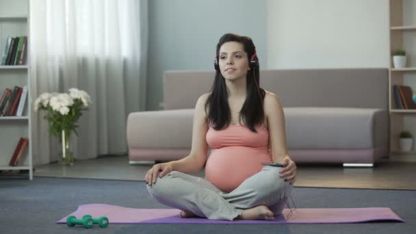 Pregnant girl listening to melodies engaging in spiritual development of fetus - Кадри, відео
