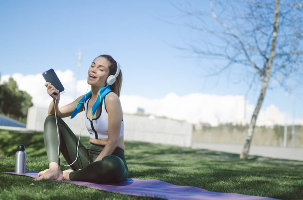 Zdravá žena odpočívá a poslech hudby s mobilním telefonem a přitom jóga a cvičení - Fotografie, Obrázek