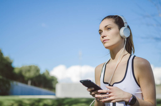 mulher saudável descansando e ouvindo música com telefone celular enquanto faz ioga e treino
 - Foto, Imagem