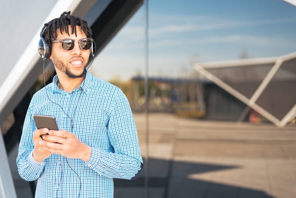 молодий чоловік використовує телефон і слухає музику крупним планом ізольовано щасливий на відкритому повітрі
 - Фото, зображення