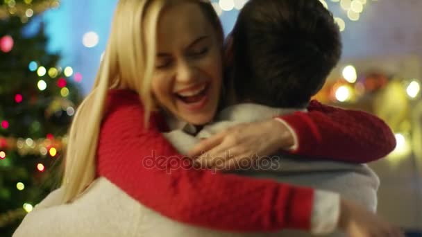 Happy Beautiful Woman Hugs Her Handsome Man. Christmas Tree and Flying Confetti in the Background. - Filmagem, Vídeo