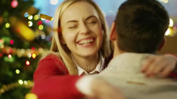 Happy Beautiful Woman Hugs Her Handsome Man. Christmas Tree and Flying Confetti in the Background. - Filmagem, Vídeo
