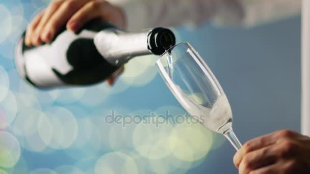 Homem vestindo camisa branca derramando champanhe no copo de champanhe. Fundo é azul com luzes embaçadas brilhando
. - Filmagem, Vídeo