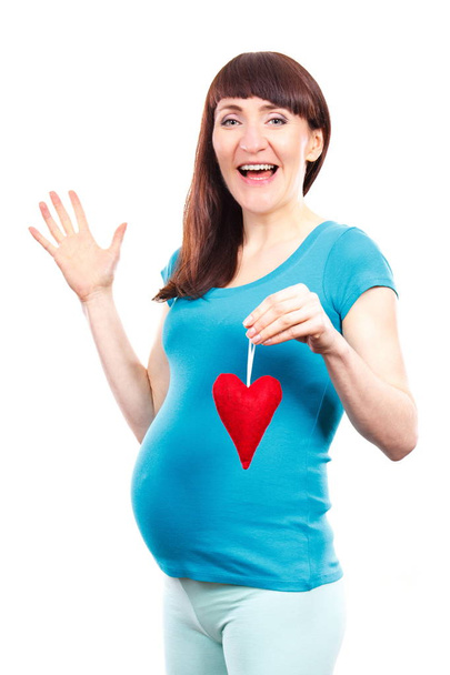 Happy delighted pregnant woman holding red heart, symbol of new life and expecting for newborn - Fotografie, Obrázek