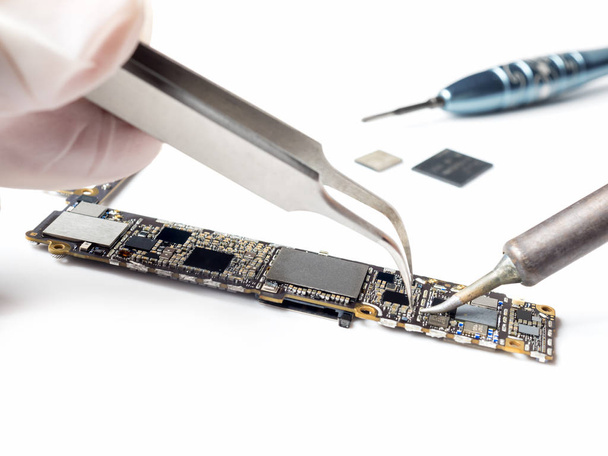 Technician replacing microchip of smartphone logic board  - Valokuva, kuva