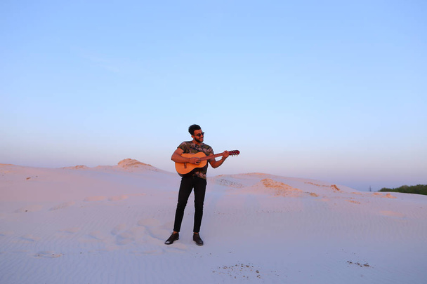 Красивий чоловік Арабські гра гітара стоячи в середині bottomle - Фото, зображення