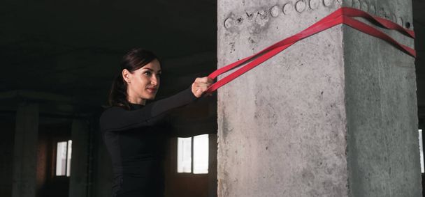 Woman athlete doing exercise with sports rubber in gym - Foto, immagini