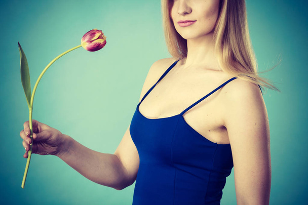 Shot on blue of woman holding tulip - Photo, image