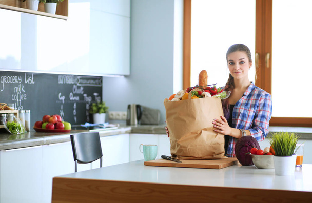 Portrait of young woman standing with arms crossed against kitchen background. - Foto, Imagen