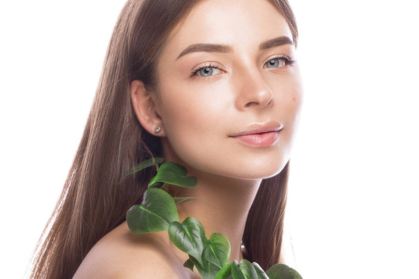 Beautiful young girl with a light natural make-up and perfect skin with Green branch in her hand . Beauty face. - Foto, afbeelding
