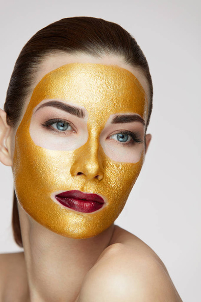 Woman Face Treatment. Attractive Female With Beauty Golden Mask  - Фото, изображение