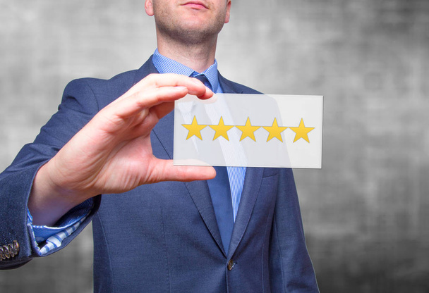 Businessman hand holding five stars isolated on grey background. - Photo, Image