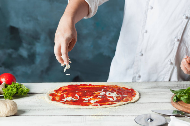 Closeup hand of chef baker in white uniform making pizza at kitchen - Fotó, kép