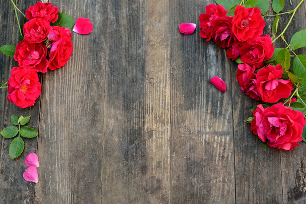 Frame of red roses on a wooden background with space for text. - Foto, Imagem