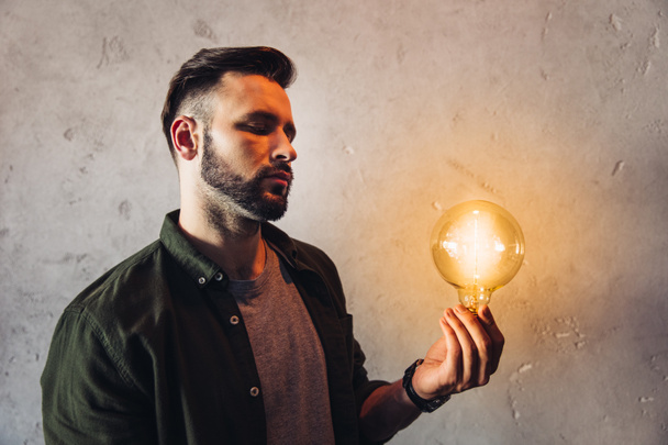 Man holding light bulb  - Foto, Bild