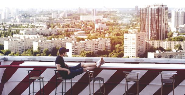 Yüksek bir binanın çatısında genç adam - Fotoğraf, Görsel