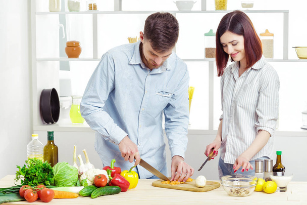Liebendes glückliches Paar bereitet in Küche gesunden Salat mit frischem Gemüse zu - Foto, Bild